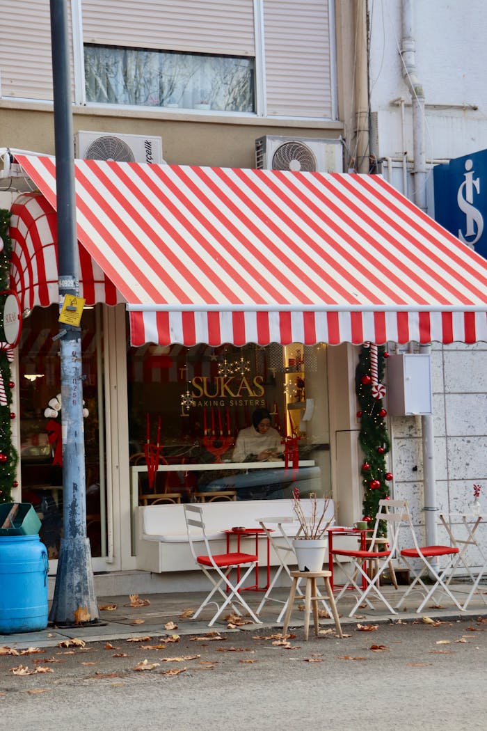 Cozy street café with red striped awning and festive decorations.
