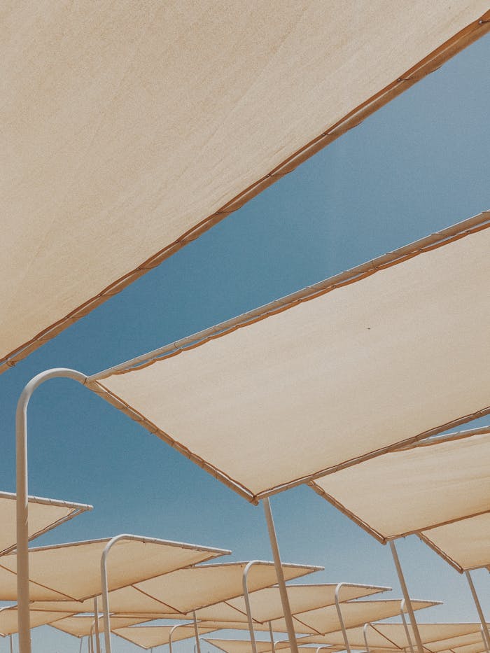 Low angle view of modern sun shades under a clear blue sky, perfect for summer concepts.